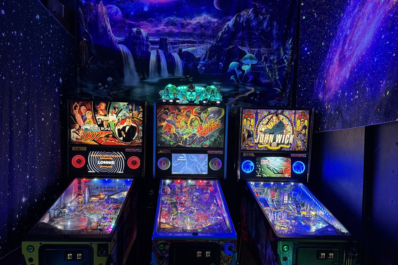 The blacklight room — a painted galaxy and waterfall mural glowing over three pinball machines
