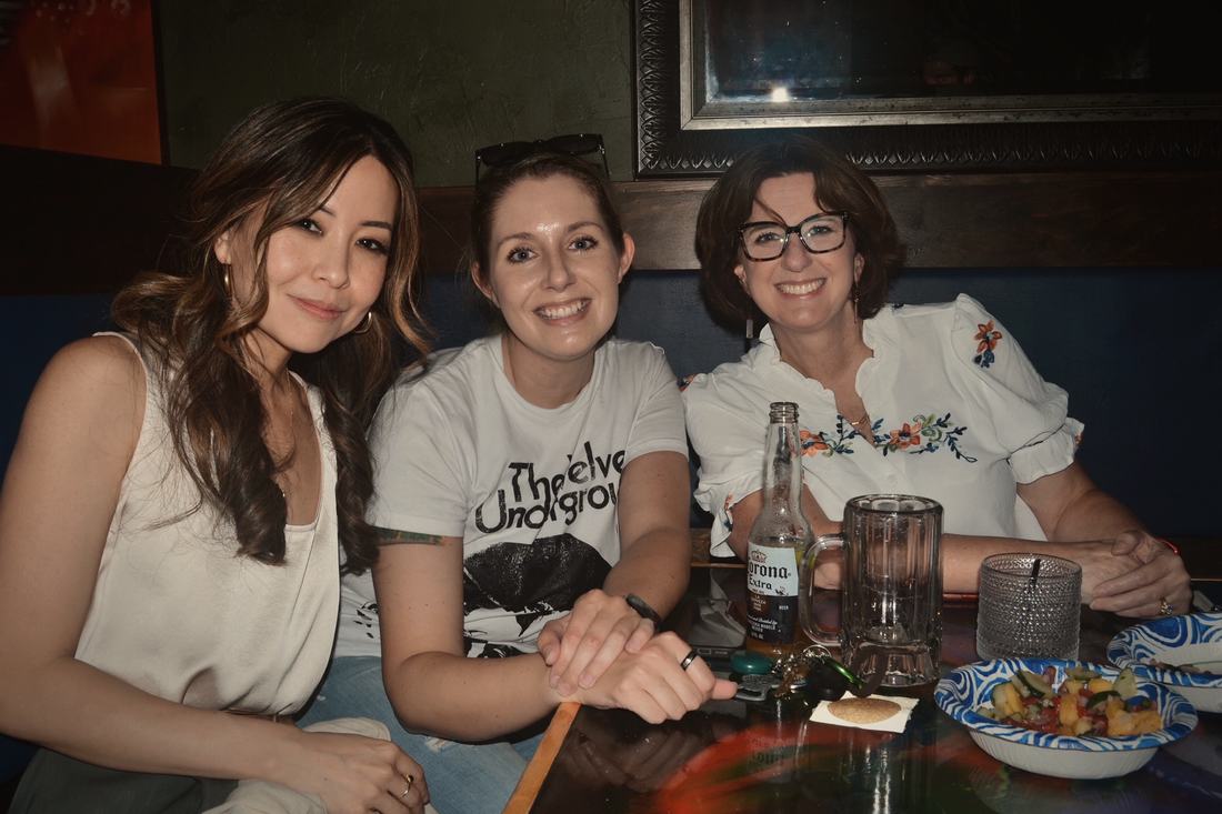 Three guests sharing a booth, with drinks and a snack on the table.