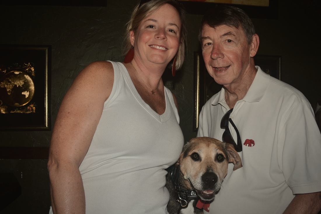 Two guests with a dog, in front of the gold world-map artwork.