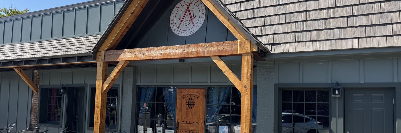 The Alcove storefront on 22nd Avenue — cedar timber entry, the crest on the gable, and patio tables out front